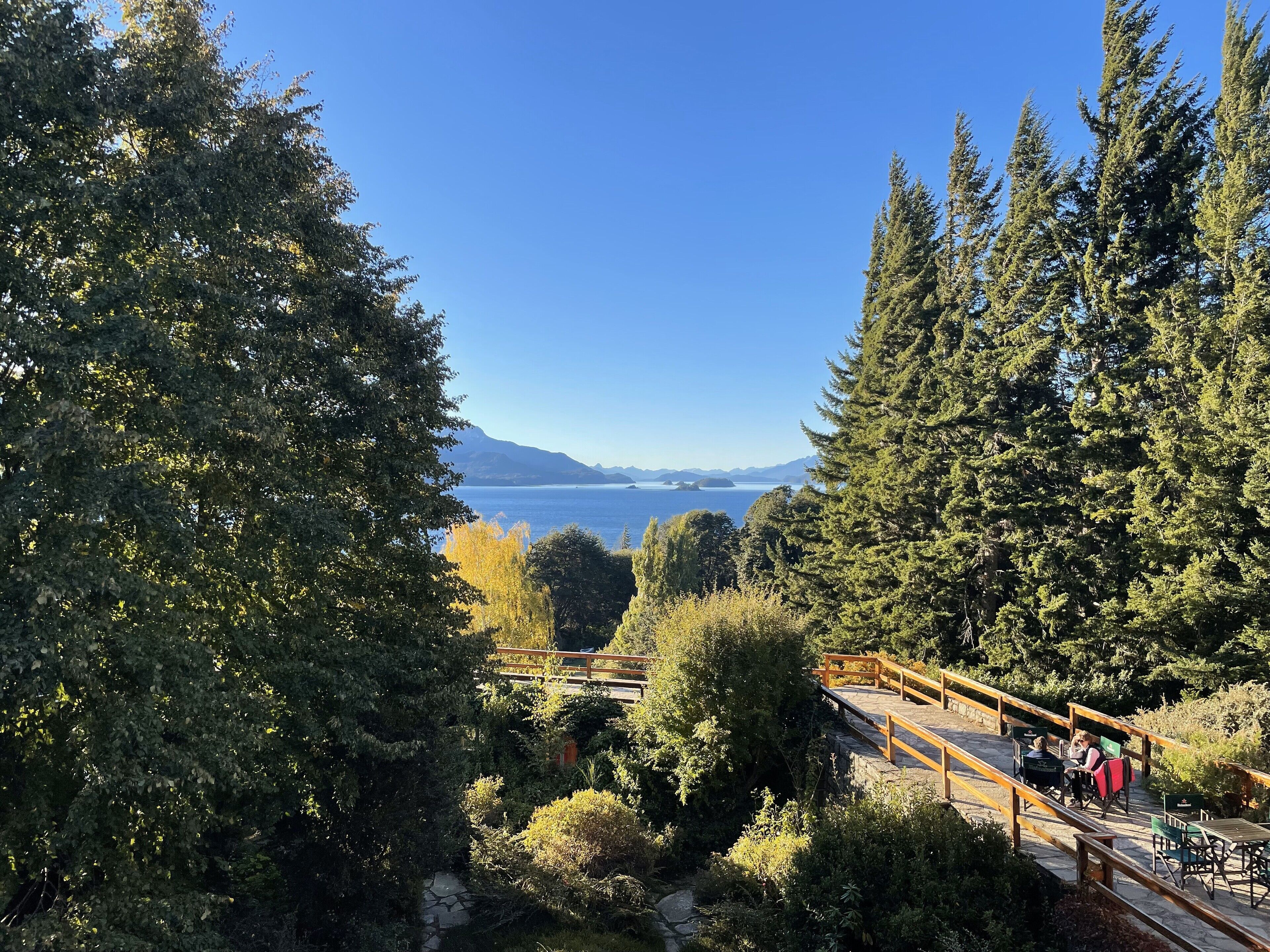 A wooden deck with outdoor seating overlooking a lake and mountains.
