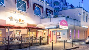 Un hotel con bar y restaurante llamado 'ElferRat' y un cartel que indica 'Mercure Hotel' en la planta baja.