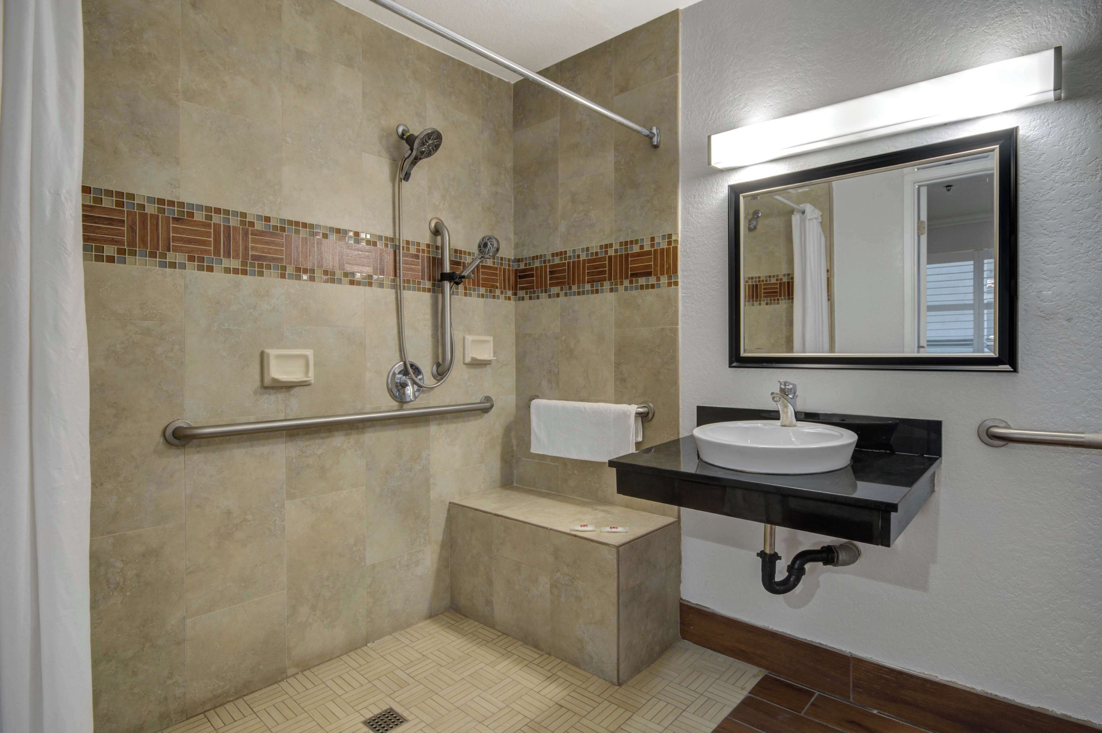 A bathroom with a shower, a sink, a toilet, and a mirror.