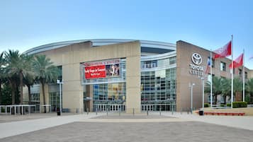 A modern building with a curved facade, a prominent Toyota Center sign, and palm trees in the foreground.