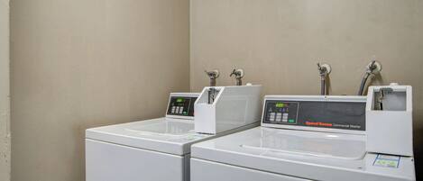 A row of commercial washers with digital displays, in a plain-walled room.