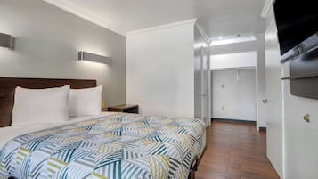 A hotel room with a large bed, a wooden headboard, a nightstand, and a wall-mounted TV.