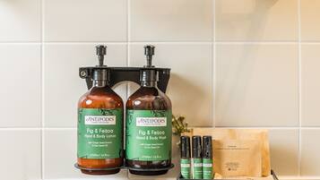 Two bottles of Antipodes Fig & Feijoa Hand & Body Lotion and two bottles of Antipodes Fig & Feijoa Hand & Body Wash on a black soap dish.