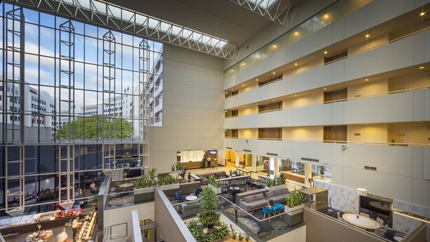A spacious atrium with multiple levels, large windows, and a central seating area with sofas and tables. - Crowne Plaza Canberra by IHG (Canberra)