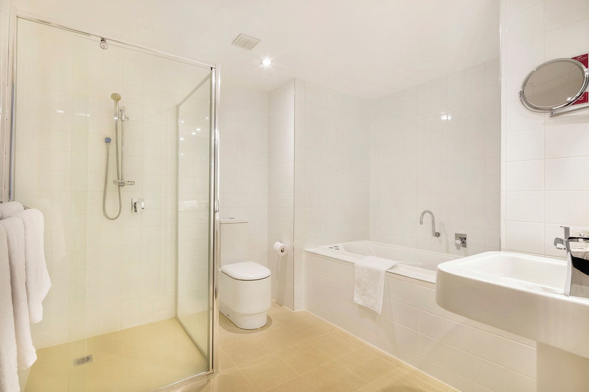 A modern bathroom with a glass-enclosed shower, a toilet, a bathtub, and a sink.