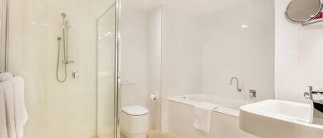 A modern bathroom with a glass-enclosed shower, a toilet, a bathtub, and a sink.