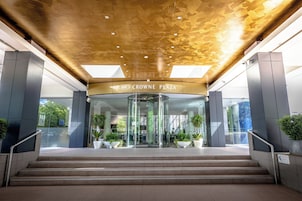 Una entrada moderna con puerta de vidrio, un letrero que dice "CROWNE PLAZA" y una escalera que sube.