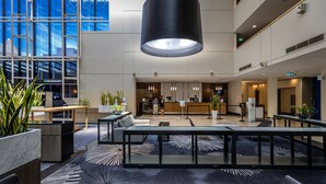 A modern lobby with a reception desk, seating area, and large windows offering views of the cityscape. - Crowne Plaza Canberra by IHG (Canberra)