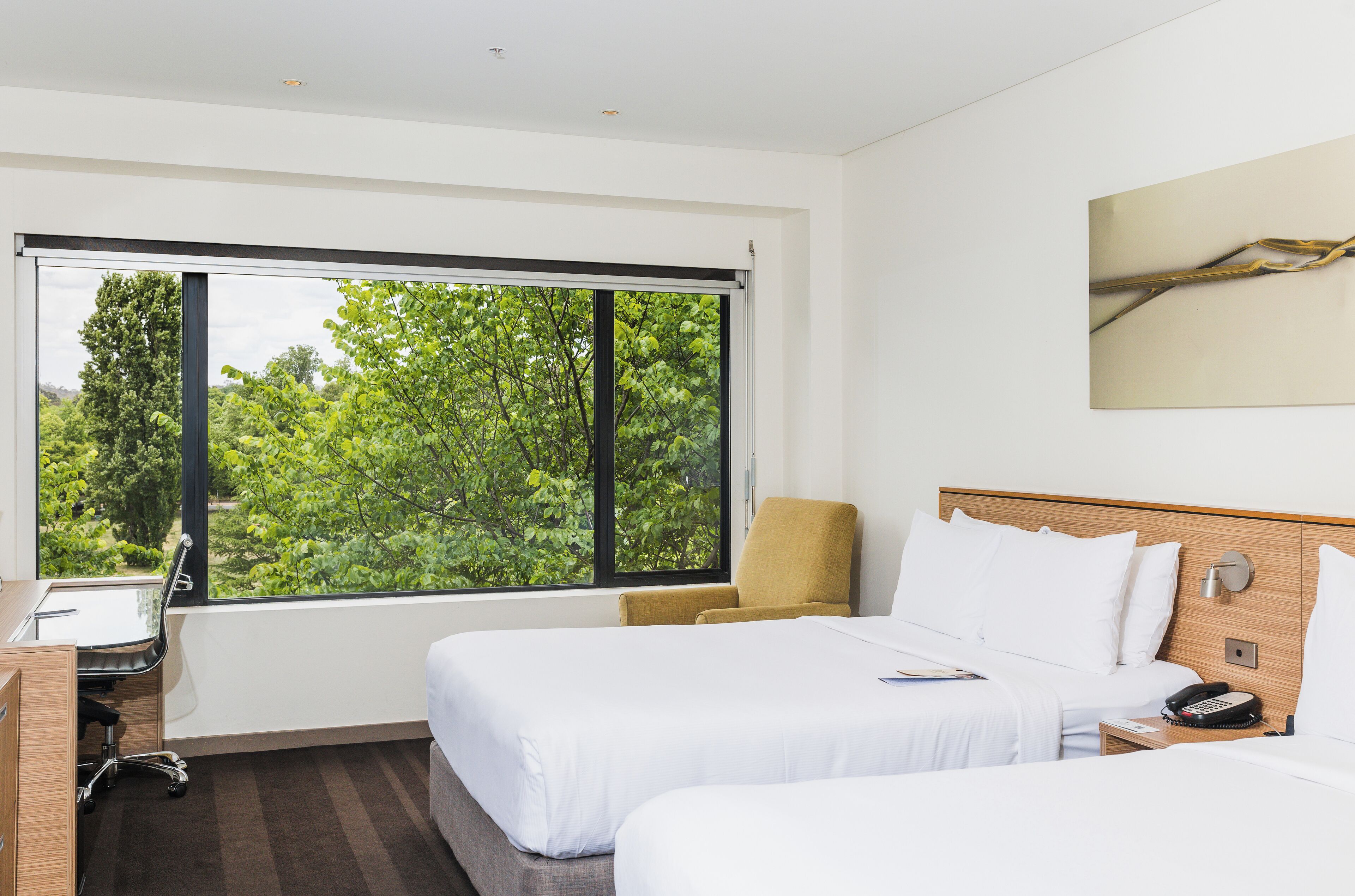 A hotel room with two beds, a desk, and a chair.