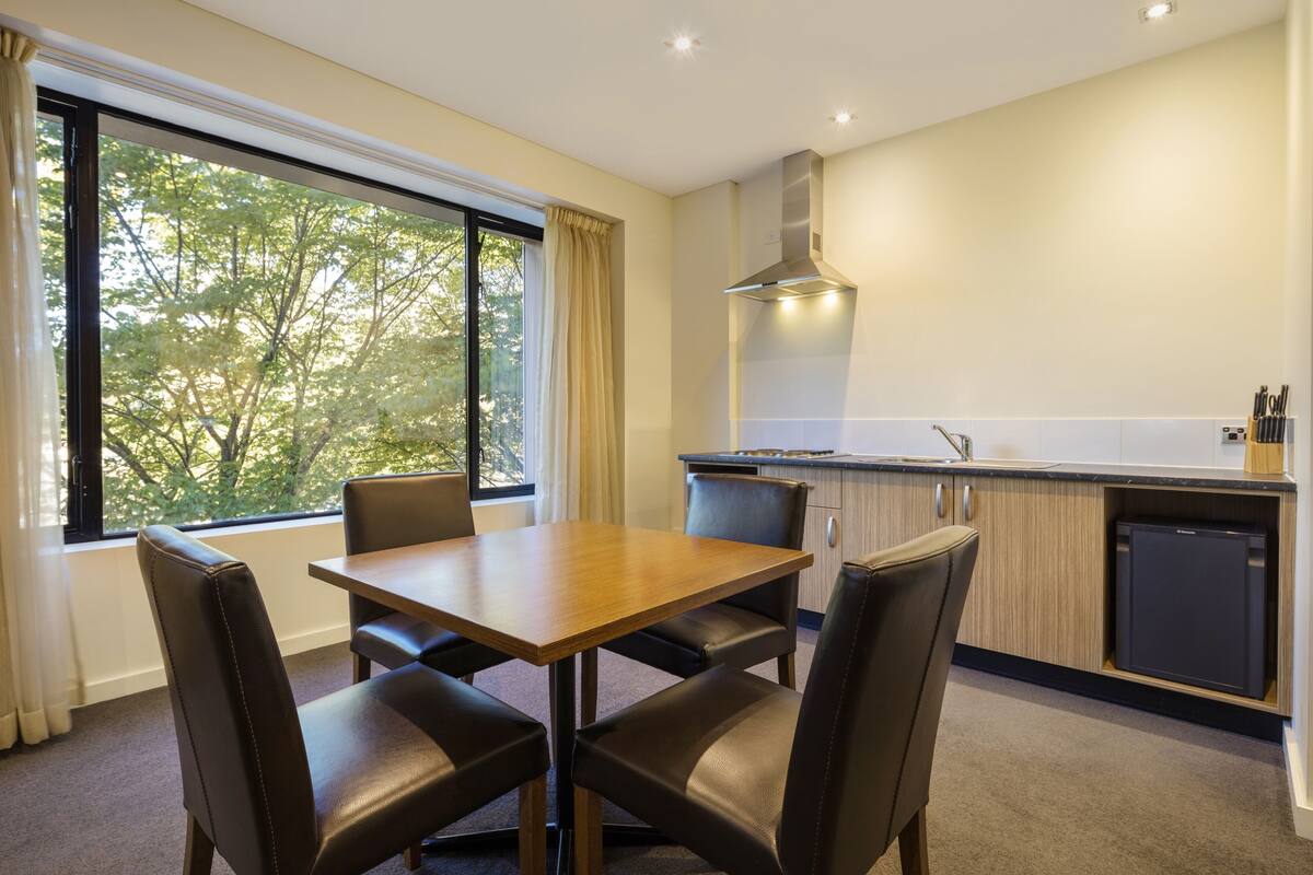 Una cocina moderna con zona de comedor, ventanas amplias y lavavajillas integrado.