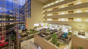 A multi-level hotel atrium with a glass facade, multiple floors, and a variety of seating areas. - Crowne Plaza Canberra by IHG (Canberra)