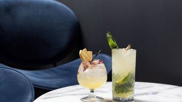 Two drinks on a marble table with a dark blue chair in the background.