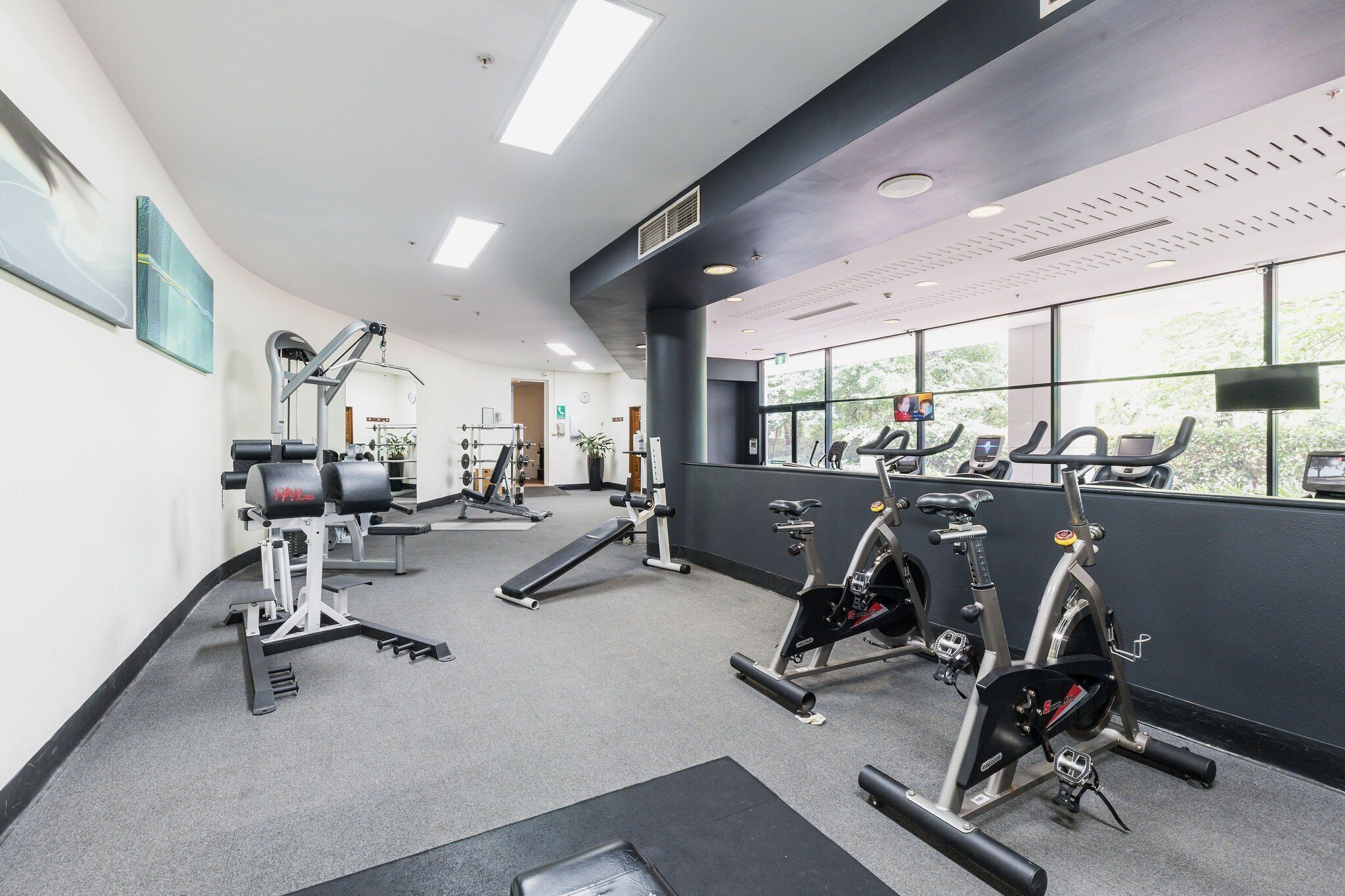 A gym with exercise equipment, large windows, and a modern design.