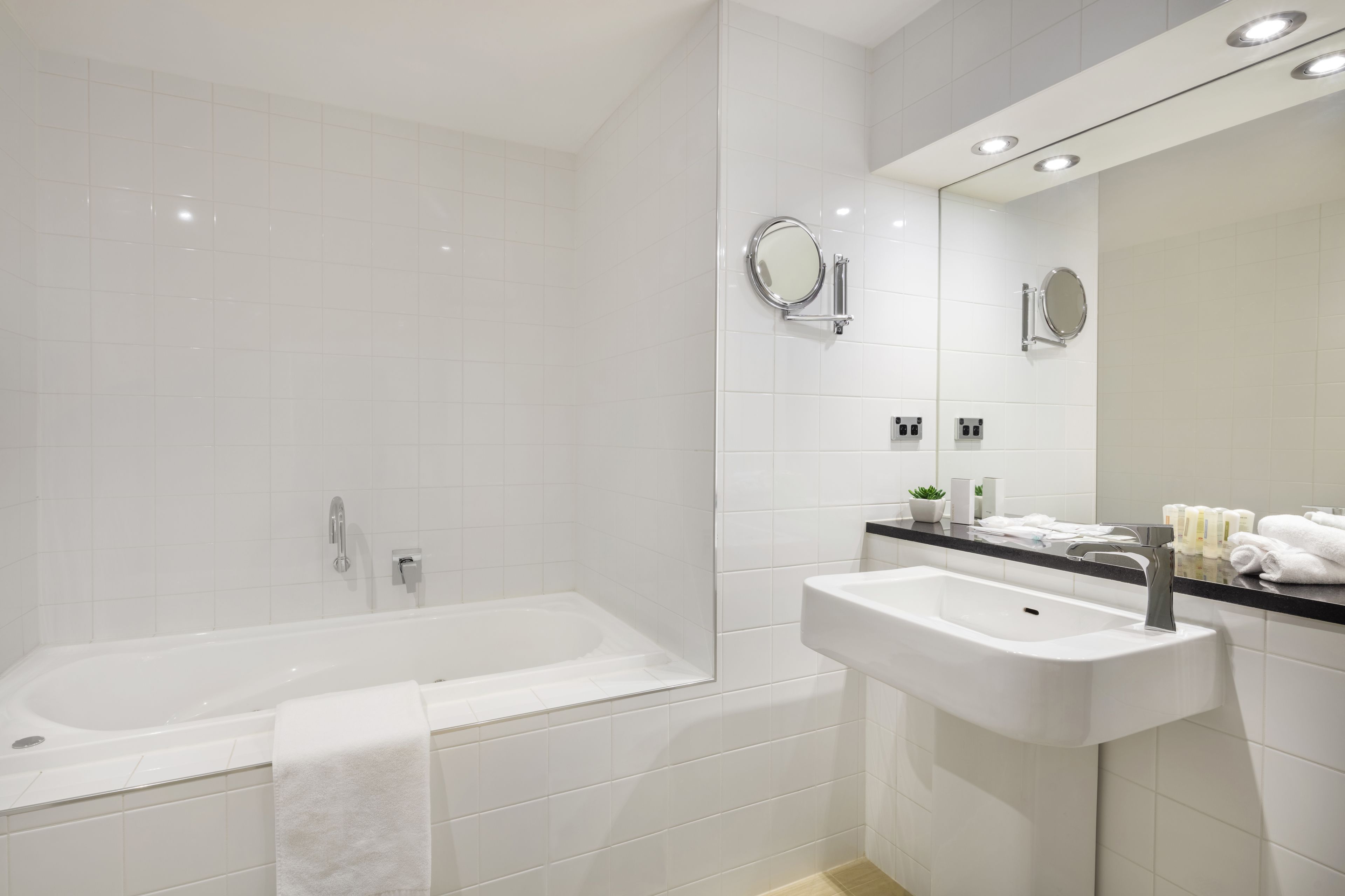A modern bathroom with a bathtub, a sink, and a mirror.