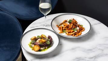 Twee porties pasta op een witte marmeren tafel met een glas witte wijn.