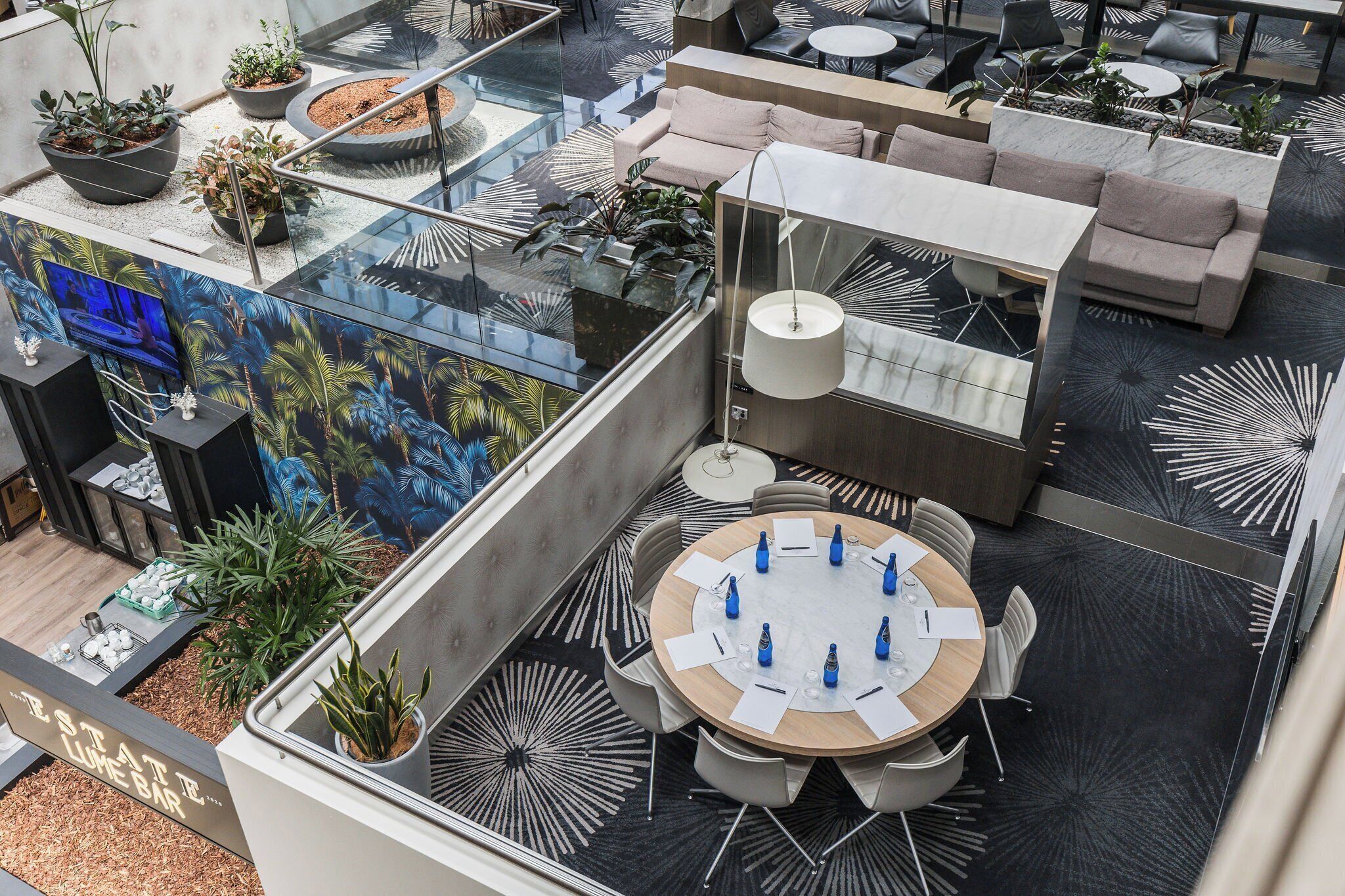 A rooftop lounge area with a round table, chairs, and potted plants.