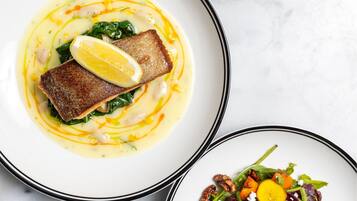 Un plato con un trozo de pescado y verduras, y otro plato con una ensalada.
