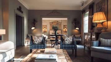 A living room with a coffee table, two armchairs, a sofa, a mirror, and a lamp.