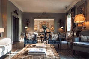A living room with a coffee table, two armchairs, a sofa, a mirror, and a lamp.