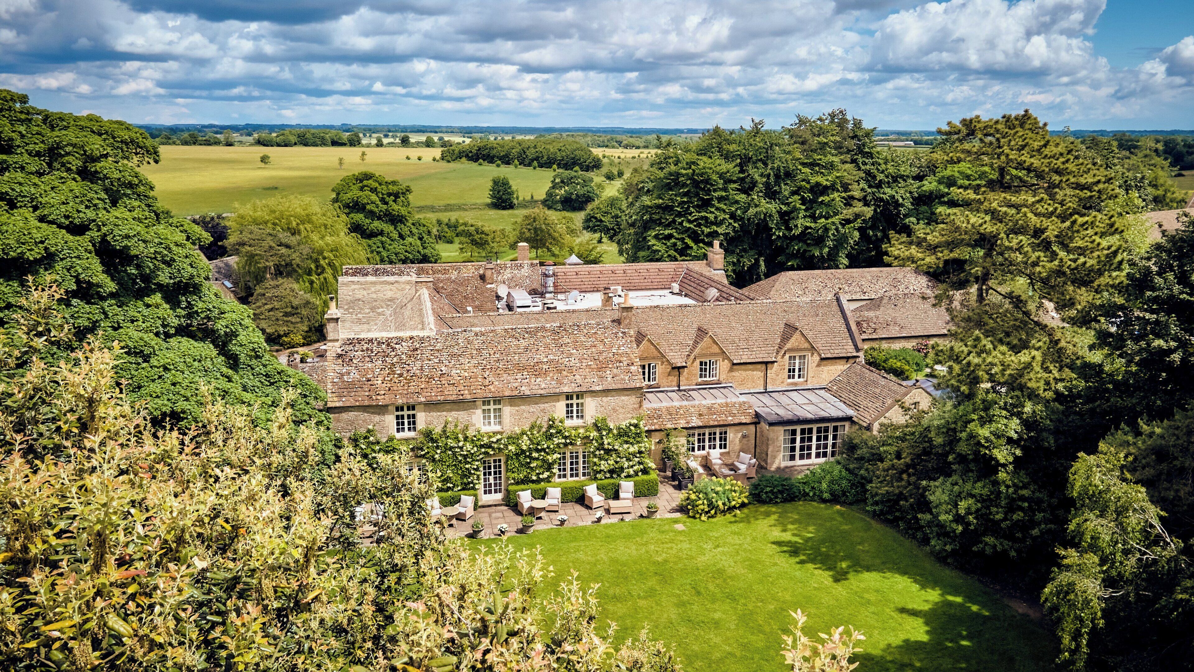 A large house with multiple rooms, surrounded by lush greenery and a well-maintained lawn.
