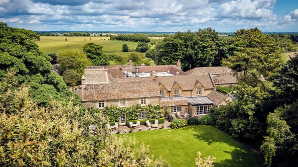A large house with multiple rooms, surrounded by lush greenery and a well-maintained lawn.