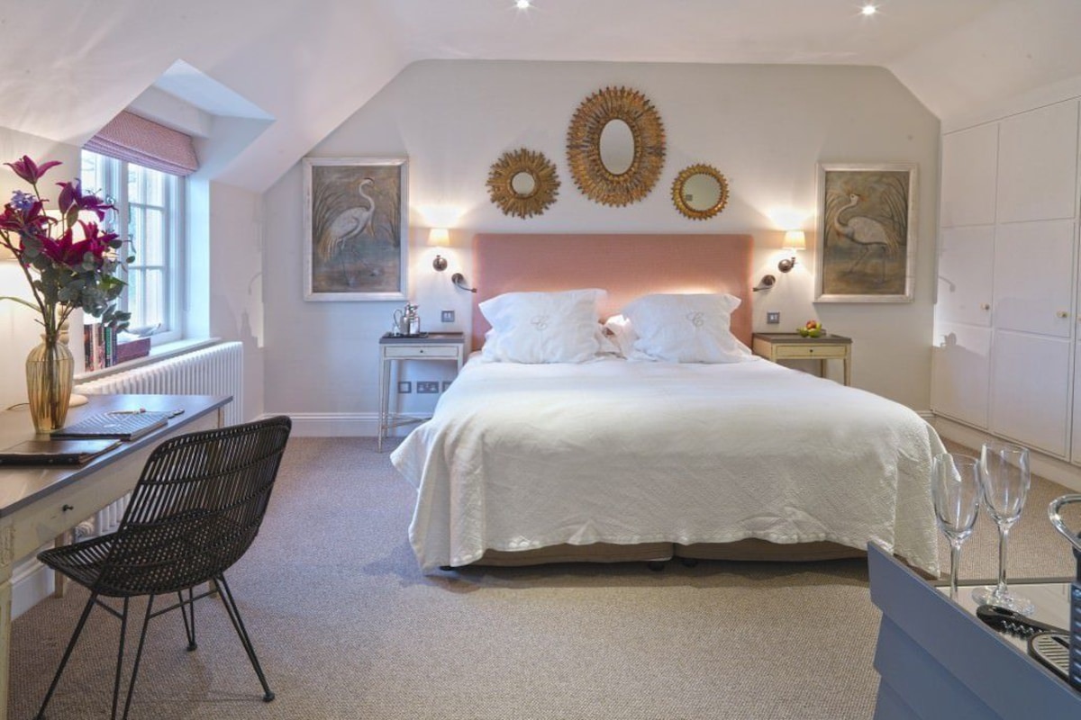 Une chambre avec un grand lit, un bureau et une chaise. Les murs sont décorés et il y a une fenêtre avec vue.