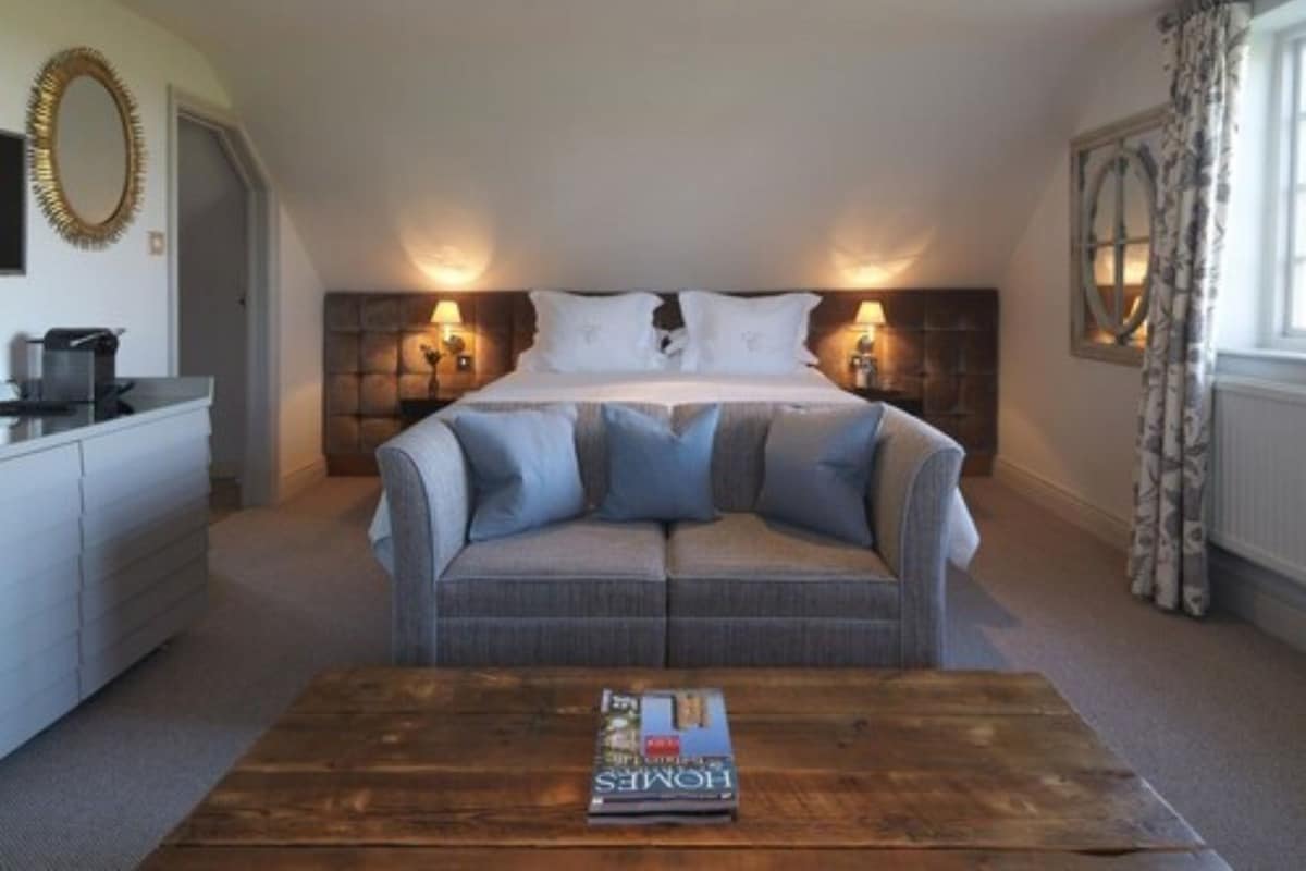 Une chambre à coucher avec un lit, un canapé, une table basse et un miroir.