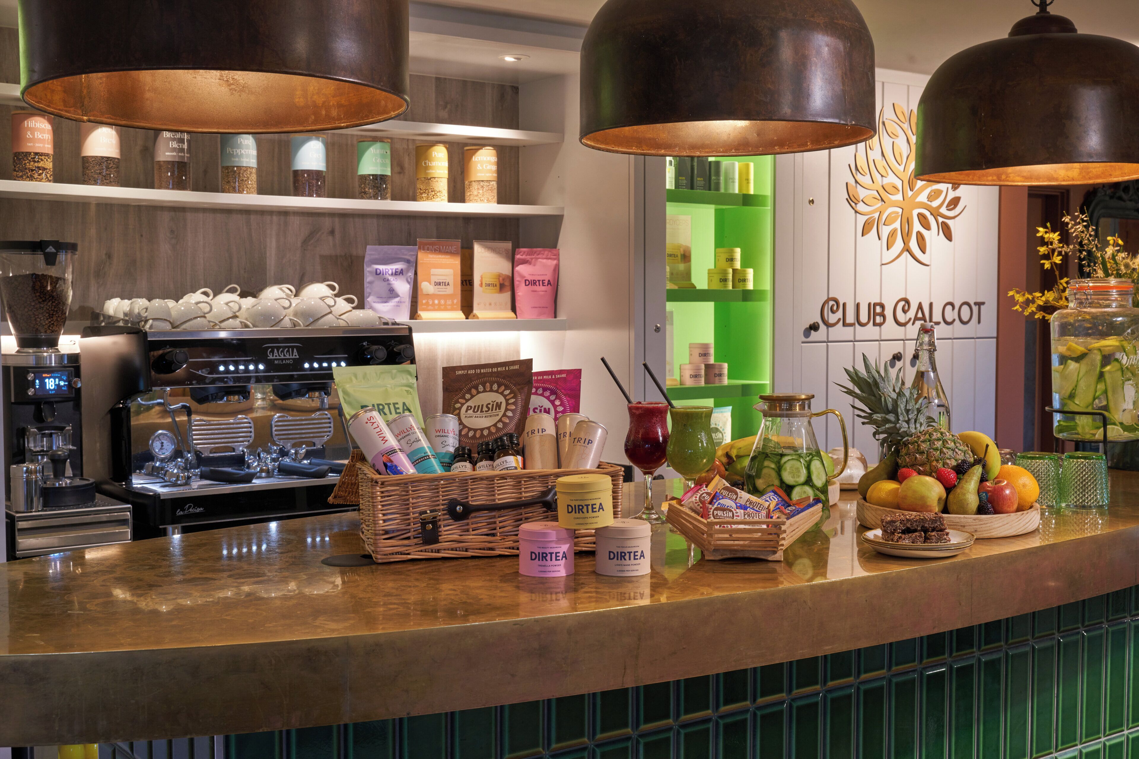A bar area with a coffee machine, various food items, and a sign for Club Calcot.