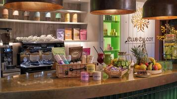 A bar area with a coffee machine, various food items, and a sign for Club Calcot.
