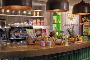 A bar area with a coffee machine, various food items, and a sign for Club Calcot.
