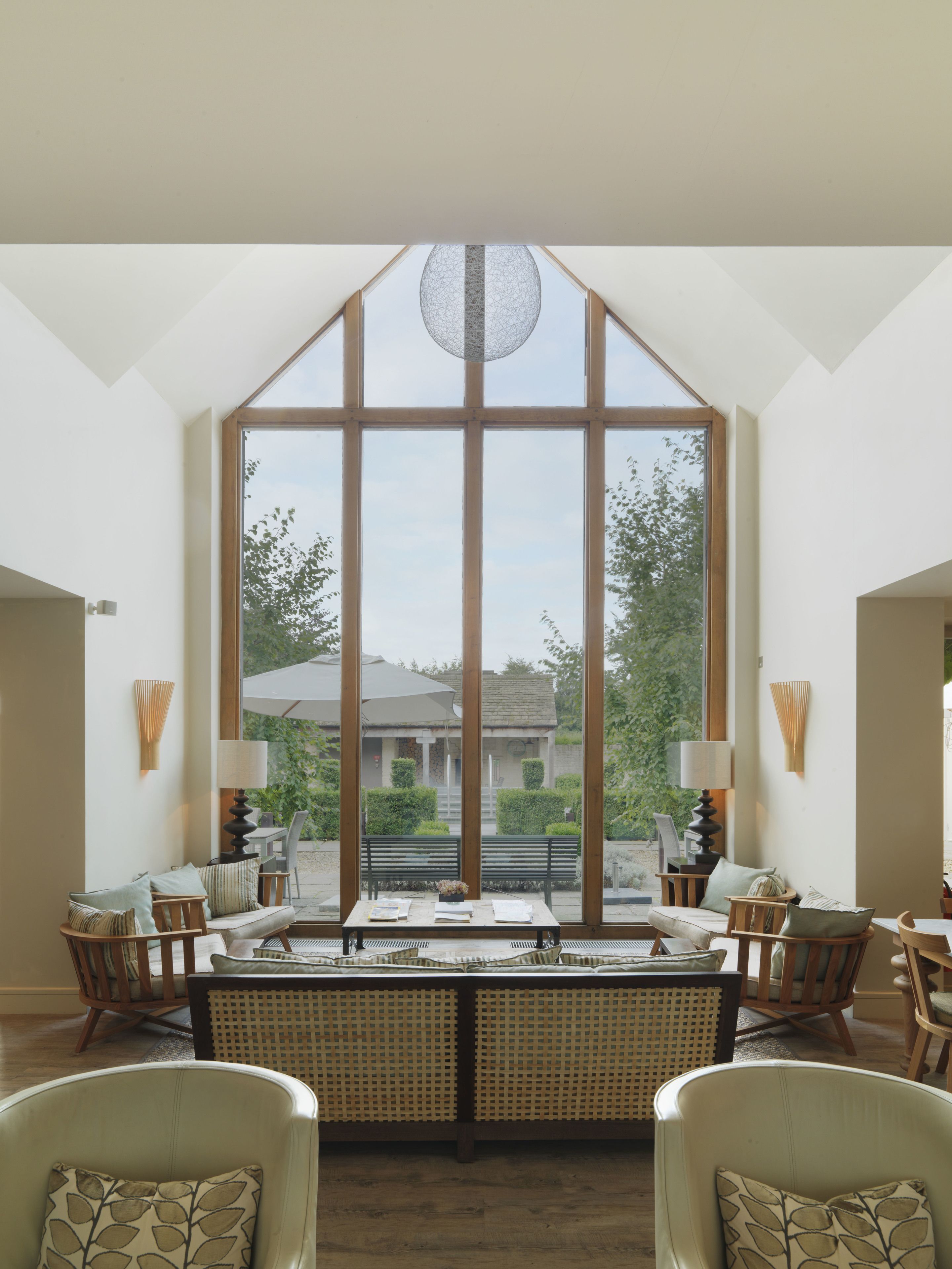 A spacious room with large windows, a central seating area with a table, and two chairs.