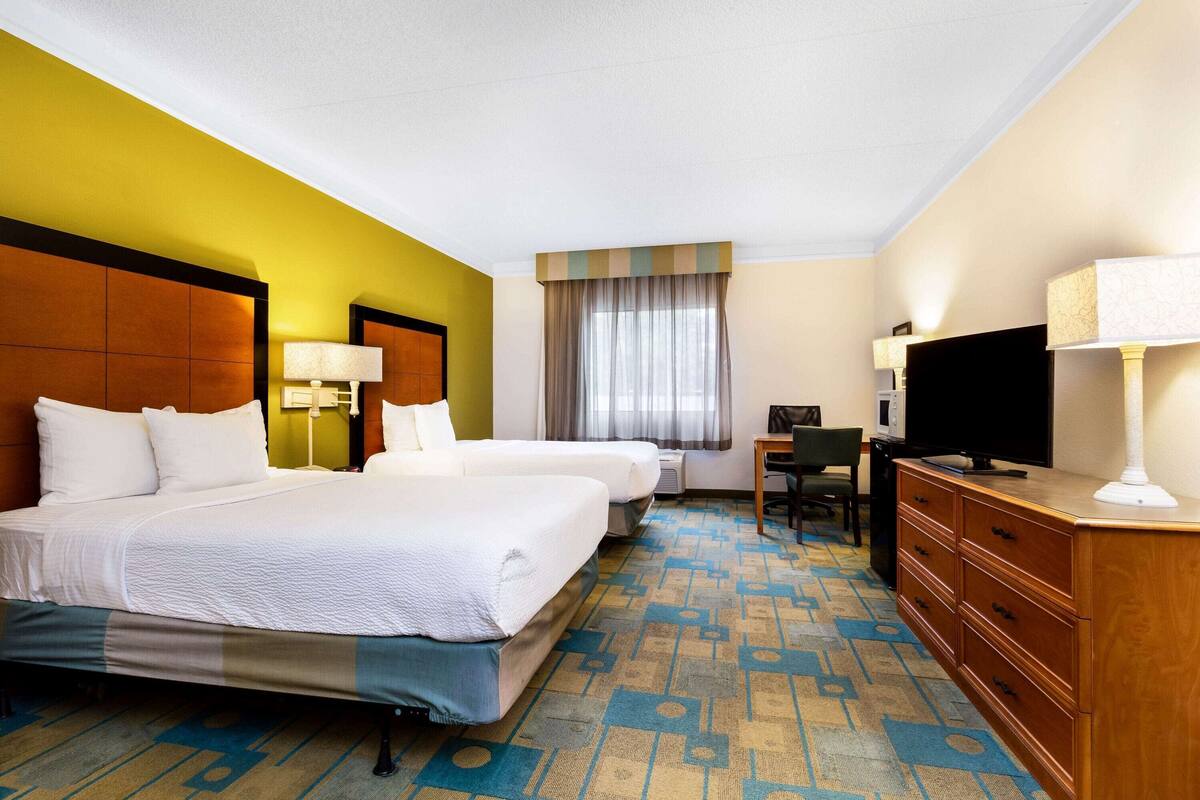 Ett hotellrum med två sängar, ett skrivbord, en tv och en byrå.