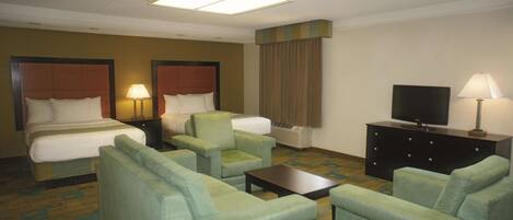 A hotel room with two beds, a sofa, a coffee table, a TV, and a dresser.