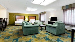 A hotel room with a bed, two armchairs, a coffee table, a TV, and a desk. - La Quinta Inn & Suites by Wyndham St. Pete-Clearwater Airpt (Clearwater)