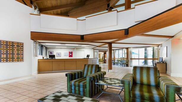 A spacious lobby with a high ceiling, wooden beams, a reception desk, and seating areas. - La Quinta Inn & Suites by Wyndham St. Pete-Clearwater Airpt (Clearwater)