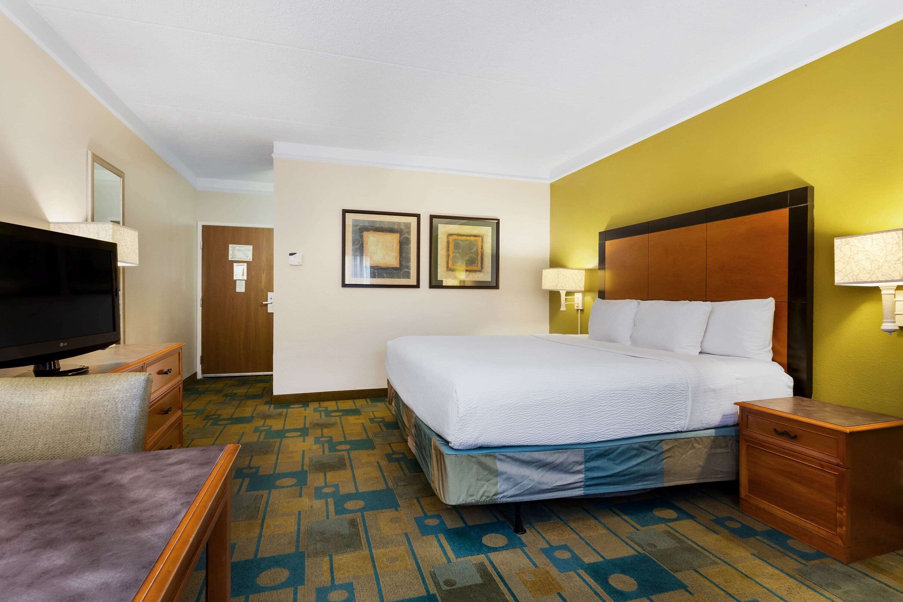 Ein Hotelzimmer mit Bett, Fernseher, Schreibtisch und Stuhl.