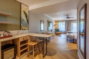 Una habitación de hotel moderna con cocina, una mesa de comedor y una sala de estar con sofá y sillas.