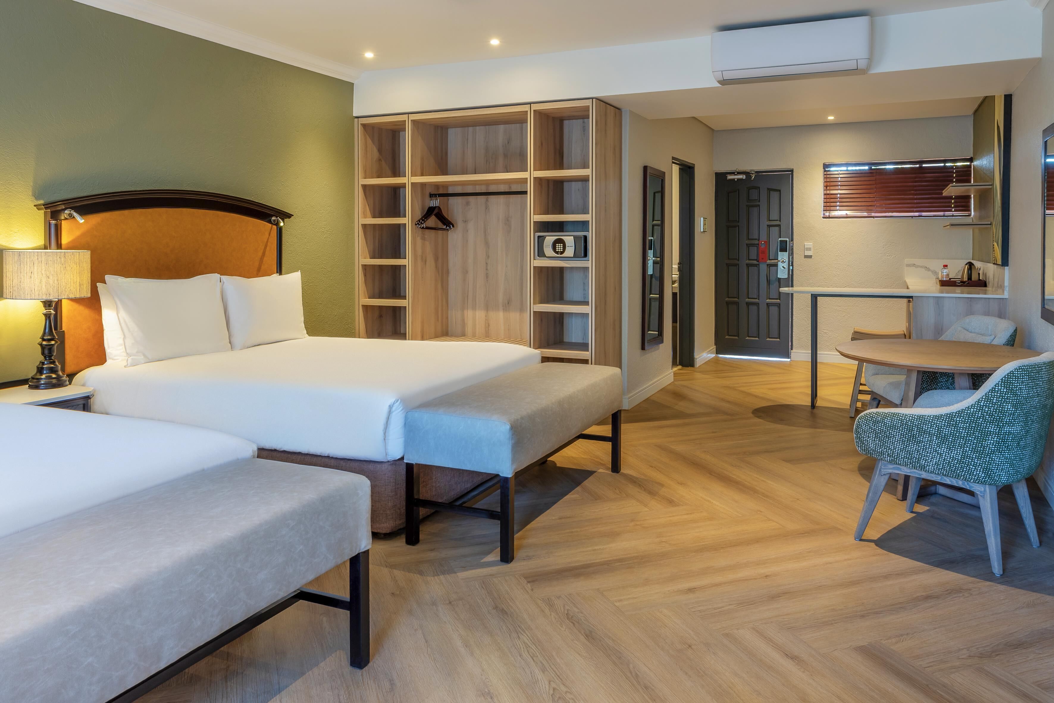 Una habitación de hotel con cama, escritorio, silla, armario y kitchenette.