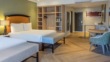Una habitación de hotel con cama, escritorio, silla, armario y kitchenette.