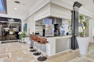 Una cocina moderna con una isla central, taburetes de bar y una planta grande en maceta.