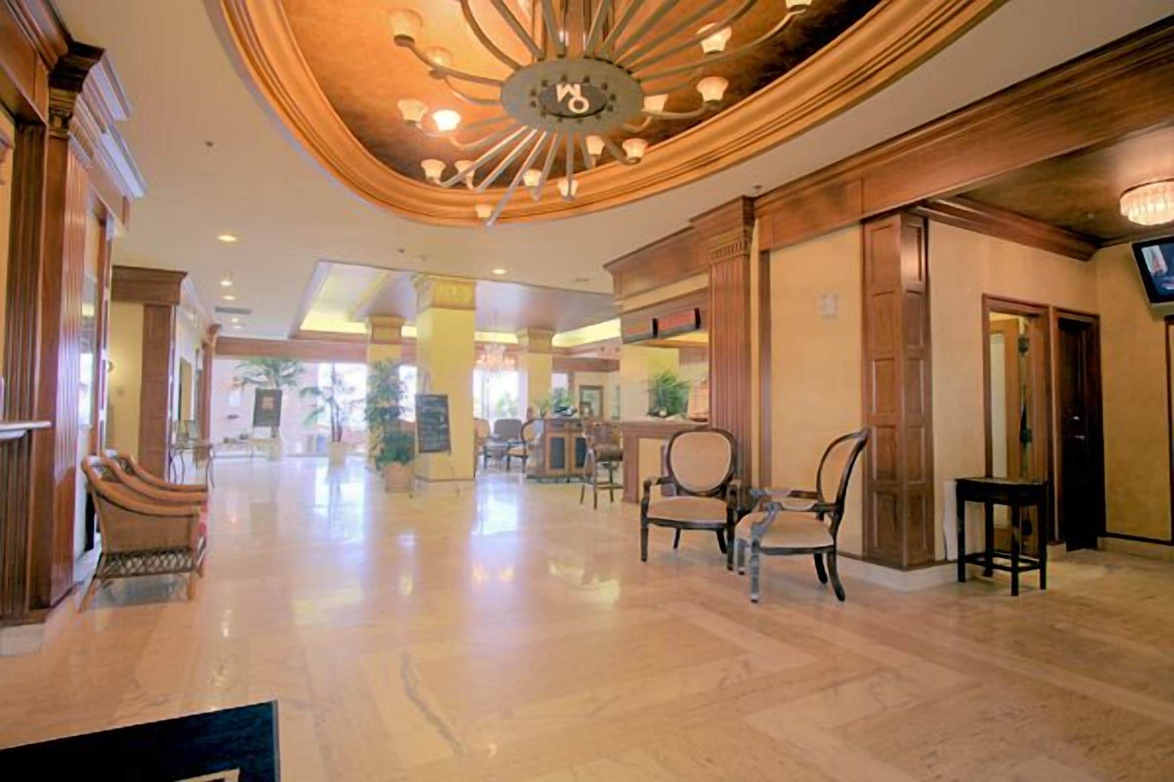 A spacious lobby with a high ceiling, chandeliers, and a polished floor.
