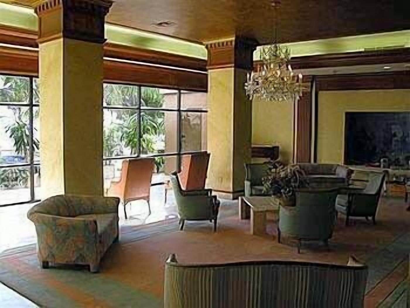A spacious lobby with large windows, comfortable seating, and a chandelier.