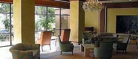 A spacious lobby with large windows, comfortable seating, and a chandelier.