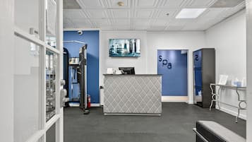 A reception area with a reception desk, a blue wall with 'spa' signage, a fire extinguisher, and a large window.