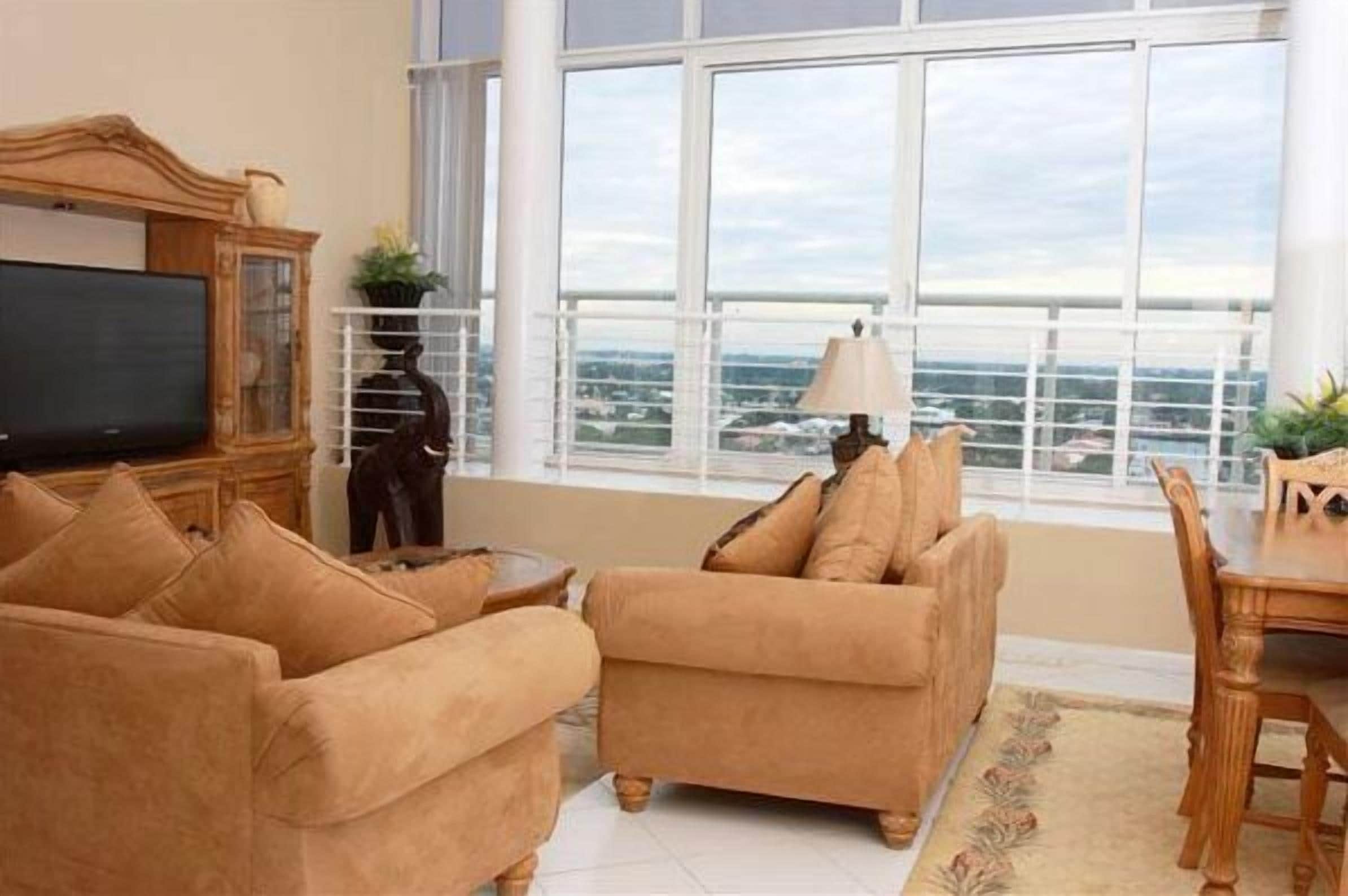 A living room with a large window, a television, and a dining area.