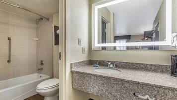A bathroom with a bathtub, toilet, and granite countertop sink.