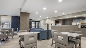 Un hall de hotel con mostrador de recepción, zona de estar y vistas al exterior.