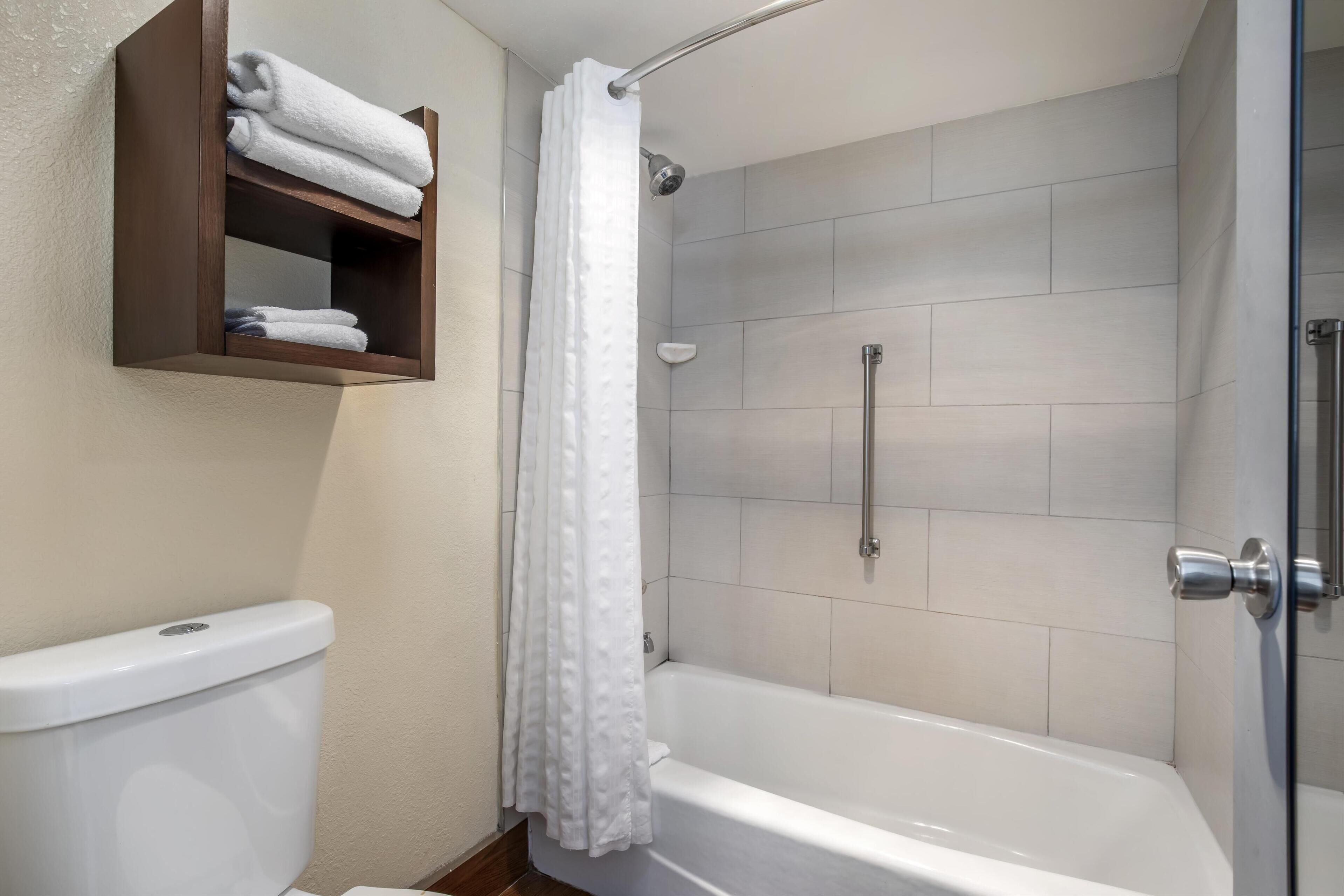 Une salle de bain comprenant des toilettes, une douche avec une porte en verre et un porte-serviettes avec des serviettes pliées.