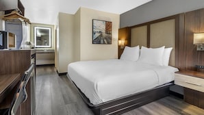 Una habitación de hotel con cama, mesita de noche y escritorio con silla.
