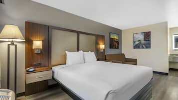 Een hotelkamer met een groot bed, nachtkastjes met lampen, een zithoekje en kunst aan de wanden.